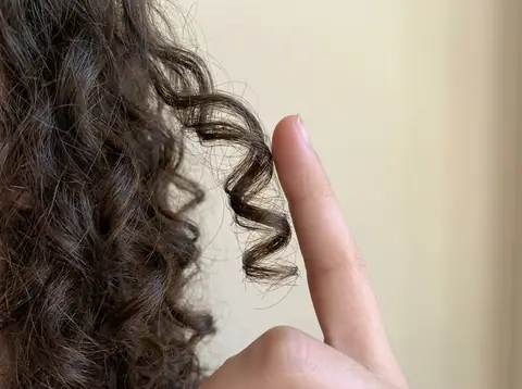 Close-up of curly hair with a finger held next to one curl for scale
